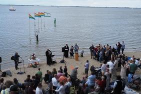Eine Menschenmenge ist beim Tauffest am Strand in Dangast versammelt.